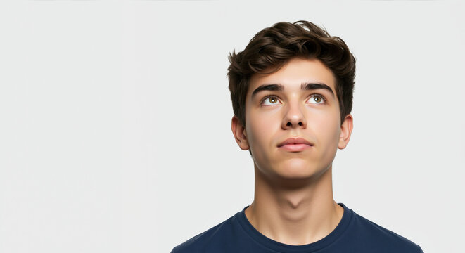 Thoughtful teenage boy looking up against white background. Student portrait for inspiration motivation and future planning concepts