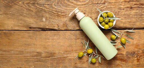 Bottle of natural cosmetic product and green olives on wooden background with space for text