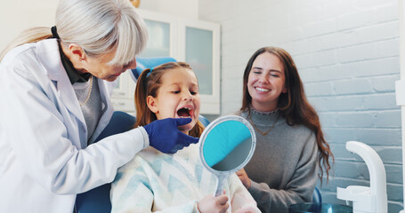 Child, dentist and oral hygiene or teeth health with advice from orthodontist with mirror by mouth....