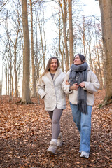 Fototapeta premium Two female friends on a walk in the forest. Friends walking through the forest. People in nature.