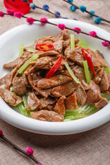 Stir-fried pork belly with hot peppers on a white round porcelain plate