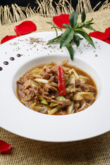 White round porcelain plate with stir-fried lamb and green onions