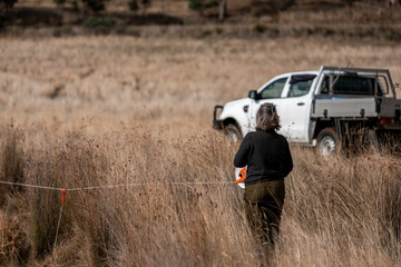female farmer reeling a electric fence a farm putting up a steel post fence with high tensile wire...