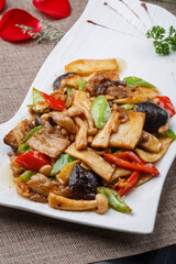 Stir-fried pork belly with mushrooms in a white rectangular porcelain plate