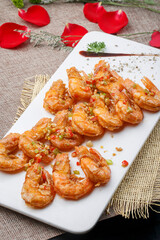 Deep-fried large shrimps with garlic paste in a white oval porcelain plate