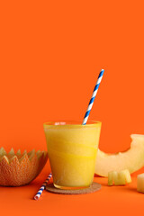 Glass of tasty melon smoothie on orange background