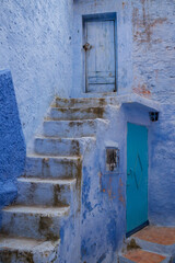 Dirty Blue Steps lead to a Wooden Door in Chefchaouen Morocco