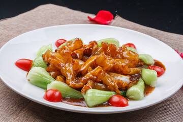 Braised sea cucumber tendons with scallions on a white round porcelain plate