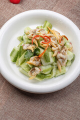 Stir-fried melon with clam meat in a white round porcelain plate