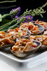 Seafood charcoal grilled purple stone clam swan eggs in a tripod-shaped porcelain plate