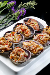 Seafood charcoal grilled purple stone clam swan eggs in a tripod-shaped porcelain plate