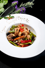Octopus fried with seafood sauce in a white round porcelain plate
