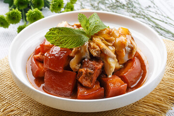 Braised pork and seafood conch slices on white round plate