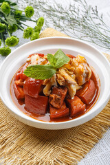 Braised pork and seafood conch slices on white round plate