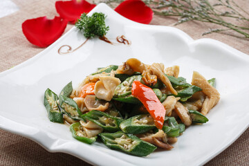 Seafood okra fried with conch meat in a square white porcelain plate with ripple edges
