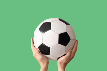 Female hands with soccer ball on green background