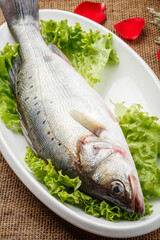 Fresh sea bass in a white oval porcelain plate