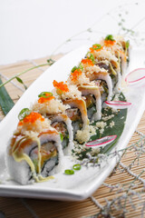 A long porcelain plate of crab roe professor rolls placed on a sushi curtain