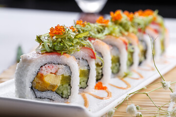 A long porcelain plate of crab roe professor rolls placed on a sushi curtain