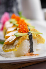 Grilled egg, crab roe and mango sushi on the sushi curtain