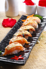 Cheese baked salmon nigiri sushi placed on a straw mat