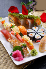 A luxurious sushi platter in a rectangular white porcelain plate is placed on a straw mat