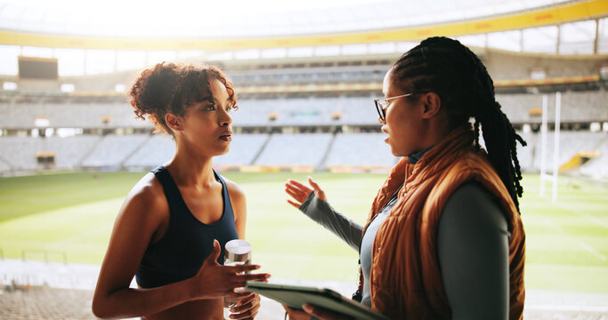 Women, sports coach and player with conversation, advice or feedback with training. People, personal trainer or professional athlete with discussion, planning or outdoor stadium with schedule or help