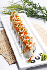 A salmon roll in a rectangular porcelain plate is placed on the sushi curtain