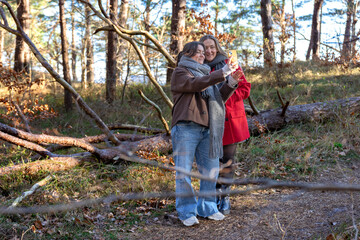 Two friends taking a selfie on their phone in the forest. Friends in nature.