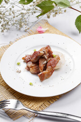 Grilled beef belly in a round white porcelain plate placed on a straw mat