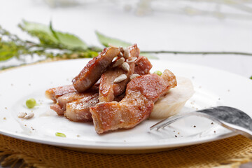 Grilled beef belly in a round white porcelain plate placed on a straw mat