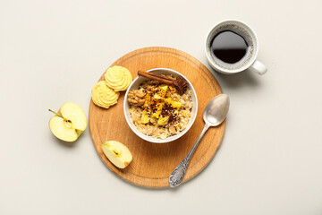 Board with tasty oatmeal, apple, cookies and cup of coffee on light background