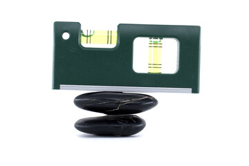 A green spirit level delicately balanced on two black stones.