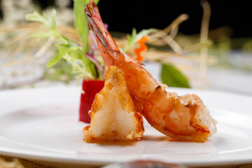A round white porcelain plate of deep-sea prawns on a straw mat