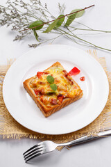 Freshly grilled seafood beef pizza on a white round plate placed on a straw mat