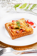Freshly grilled seafood beef pizza on a white round plate placed on a straw mat
