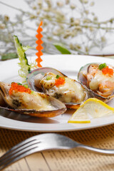 Baked mussels with mozzarella cheese in a round porcelain plate on English wrapping paper