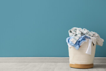 Laundry basket with dirty clothes near blue wall