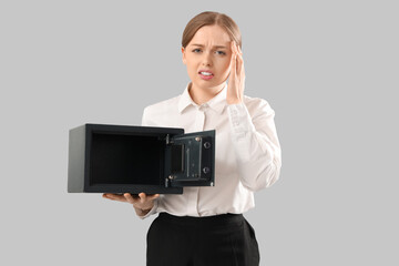 Bankrupt businesswoman with empty safe on light background