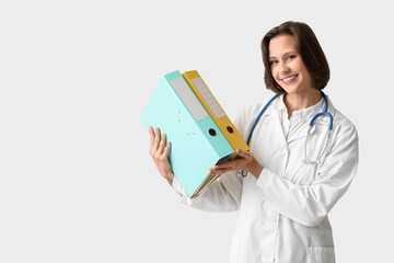 Beautiful female doctor with folders on white background