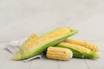 Fresh corn cobs with napkin on white tile table