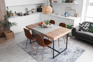 Statuettes, houseplant and wicker bowl on table in dining room