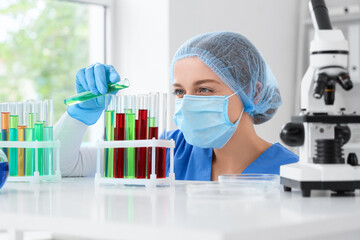 Female chemist with test tubes at table in laboratory, closeup