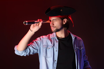 Young pirate with spyglass on dark background