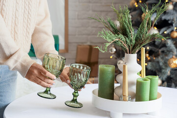 Young woman putting glasses in dining room on Christmas eve, closeup