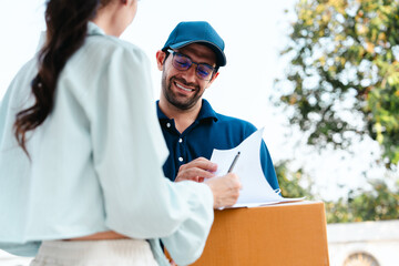 A woman receives a package from a delivery man during rush hour in front of her house.