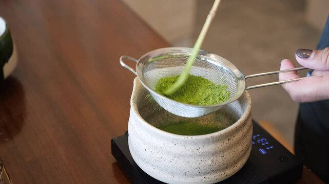 Matcha tea brewing Japanese style with fine sieve ceramic bowl bamboo scoop and whisk creating smooth traditional green tea experience