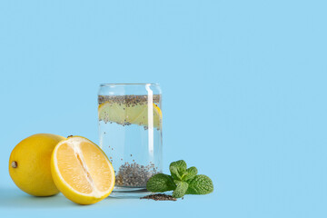 Glass of water with chia seeds, lemons and mint on blue background