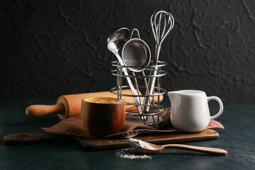 Set of kitchen utensils with flour on dark background