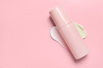 Bottle of cosmetic product with sample on pink background